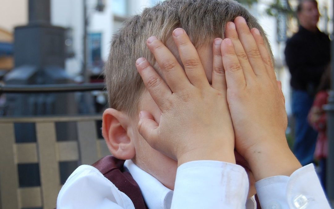 Boy with his hands covering his face