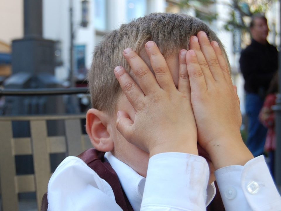 Boy with his hands covering his face