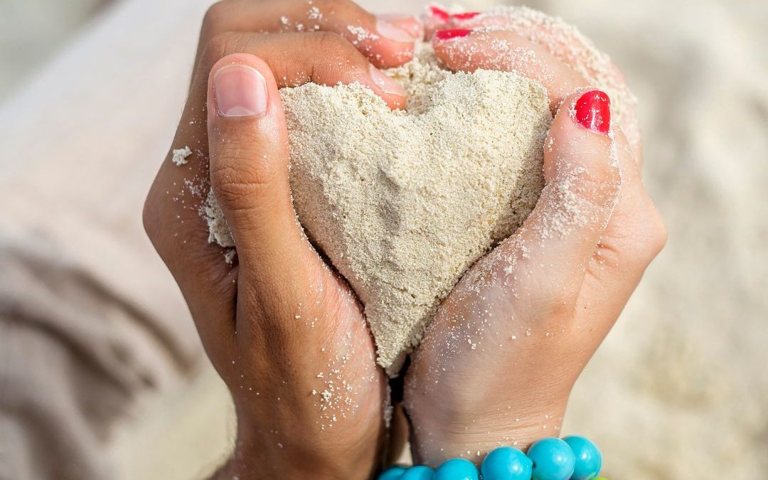 Two hands holding a sand heart