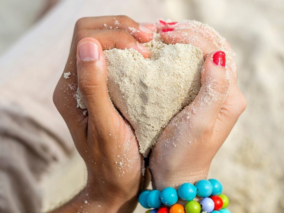 Two hands holding a sand heart